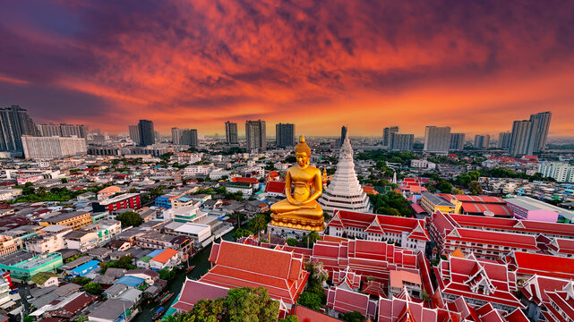 Spectacular aerial view of the giant golden Buddha statue and stupa at Wat Paknam Bhasicharoen with dramatic sky and sunbeams in Thailand.