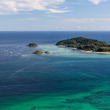 Aerial view of Koh Adang island and smaller rocky islets in the turquoise waters off the coast.
