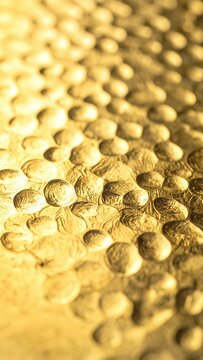 Shimmering with warm light, this luxurious hammered gold metal texture evokes feelings of opulence and elegance. Perfect abstract backdrop for design projects, no people present.