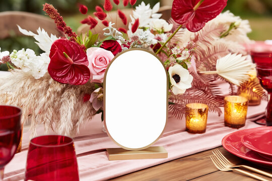 Romantic wedding table arrangemen with blank oval tanle number in front of a lush floral centerpiece