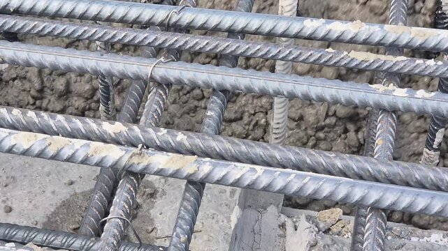 Slow motion footage of fresh concrete slowly spreading and flowing underneath the rebar matrix.