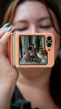 A girl with bangs and turquoise nails takes a photo of a photographer