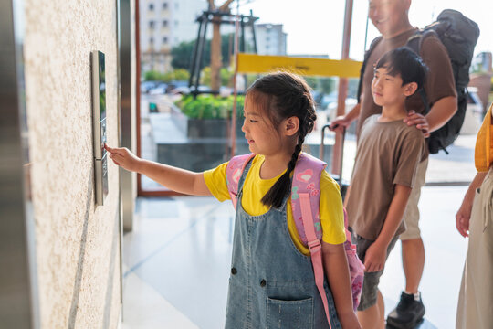 Young girl presses the elevator button for her family.