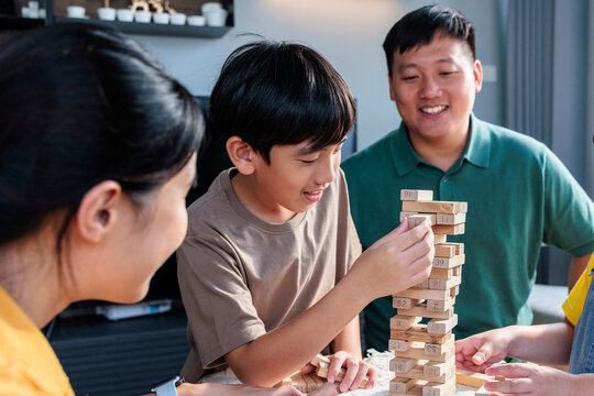 A happy family plays a wooden block tower game.