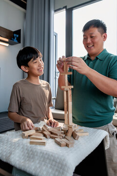 Father and son building a wooden block tower together.