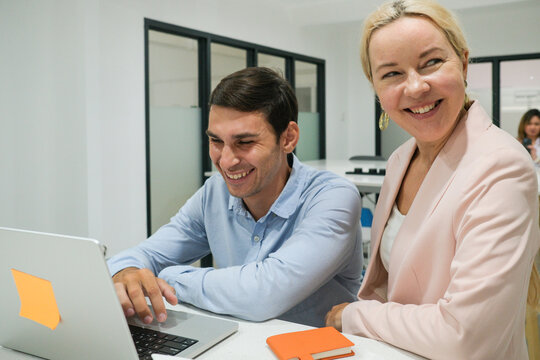 Smiling business colleagues working together on laptop