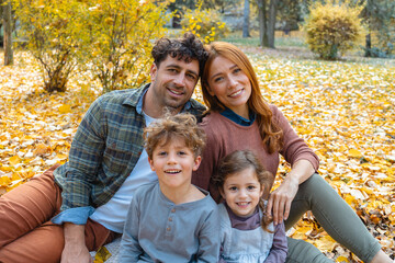 Fototapeta premium Happy family of four enjoying a beautiful autumn day in the park
