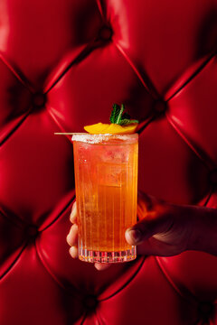 Vibrant orange cocktail against a red tufted leather background
