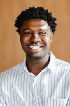 Smiling Man in Striped Shirt With Brown Background