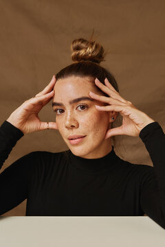 Woman with naturally freckled skin and her hair up 