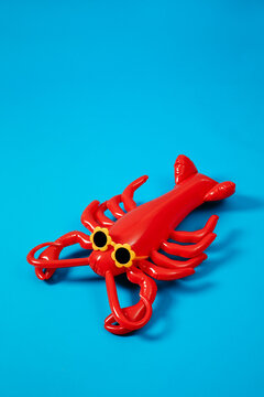 inflatable lobster wearing flower-shaped sunglasses on blue