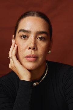 Woman with freckles wearing pearl jewelry looking at camera