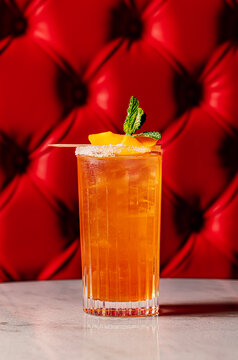 Vibrant orange cocktail against a red tufted leather background