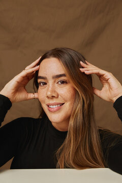 Smiling woman posing with hands on her head
