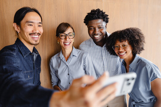 Group of Four People Taking a Selfie in a Bright Indoor Space