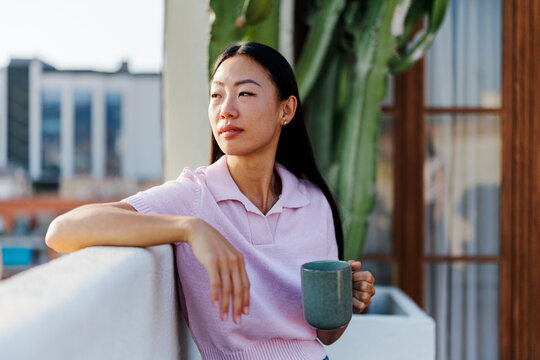 Woman enjoying morning coffee on urban terrace