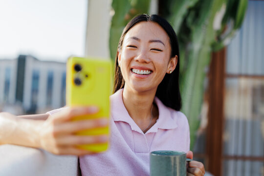 Long-haired woman looking at her phone while holding a cup of coffee