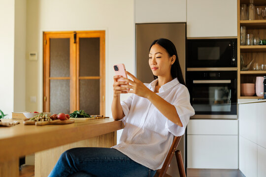 Woman  using smartphone in modern kitchen home setting