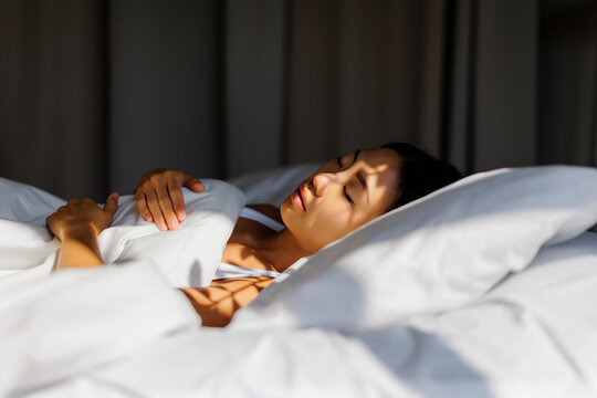 Woman sleeping peacefully in bed with morning light