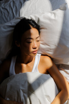 Woman resting peacefully in bed with morning sunlight