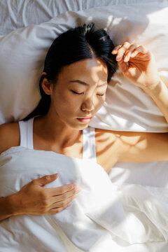 Woman sleeping peacefully in bed with morning light