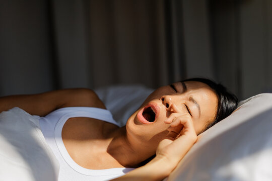 Woman yawning and waking up in morning light