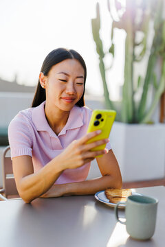 Woman enjoying morning breakfast using smartphone online