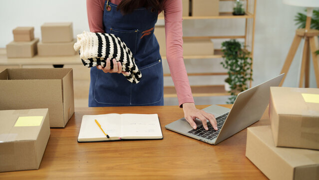 Asian woman managing online orders and packing for business at home