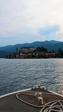 San Giulio Island on Lake Orta, Piedmont, Italy. 4K vertical video footage from boat featuring the historic basilica and picturesque lakeside scenery surrounded by Alpine landscapes