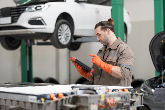 EV car repair, maintenance, inspecting services. Mechanic diagnosing battery pack, component checks, electric car vehicles battery, electric car software update, testing and install at auto workshop