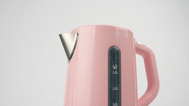 A slow close-up pan moves across the top of a pink electric kettle, revealing its spout, water level window with liter markings, and handle.