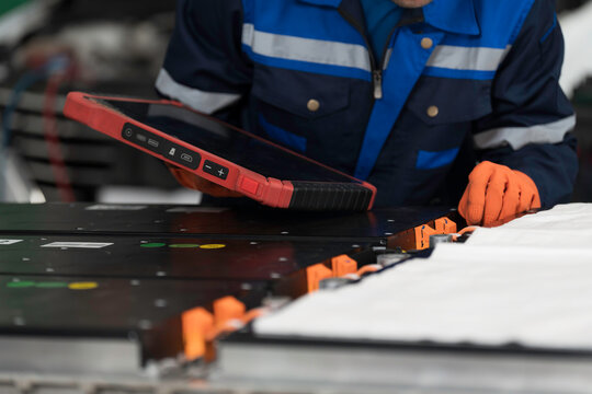 High-voltage battery checks, maintenance. Technician or Mechanic wearing protective gloves diagnosing electric car vehicles battery, component checks at auto workshop. Software updates