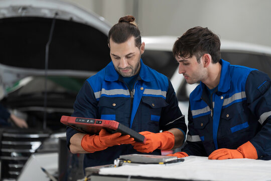 Electric vehicle car services. EV car. Diagnostic battery pack. Team of technician or Mechanic wearing protective gloves diagnosing electric car vehicles battery, component checks at auto workshop