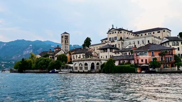 San Giulio Island on Lake Orta, Piedmont, Italy. 4K video footage from boat featuring the historic basilica and picturesque lakeside scenery surrounded by Alpine landscapes