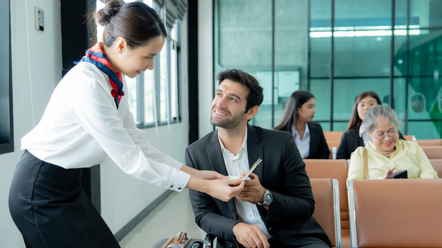 A professionally dressed passenger receives assistance from a service employee while preparing for air travel in a modern airport.