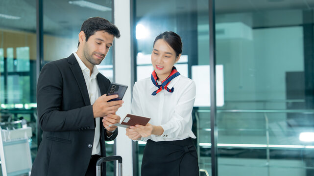 An airport service agent guides a traveler while providing digital information and personalized assistance in a modern terminal.