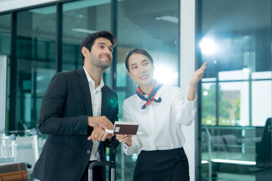 Airport staff guide a traveler through a modern terminal while providing digital information and personalized passenger assistance.