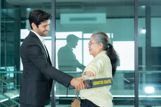 A security professional conducts a personal screening with portable equipment as part of routine airport security and passenger protection. 