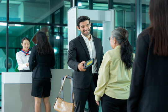 Business passenger receives assistance from airport staff during a routine security procedure in a modern airport terminal.