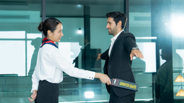  A security officer uses a handheld scanner to screen a businessman at an airport checkpoint highlighting passenger safety and access control. 