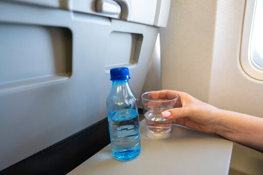 Woman holding plastic glass of water on the aircraft for drinking during the flight