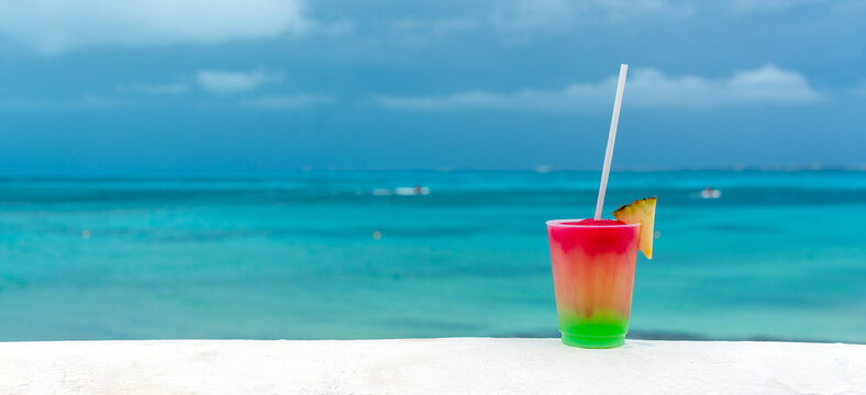 Cocktail with caribbean sea on background. Concept of beautiful tropical vacation