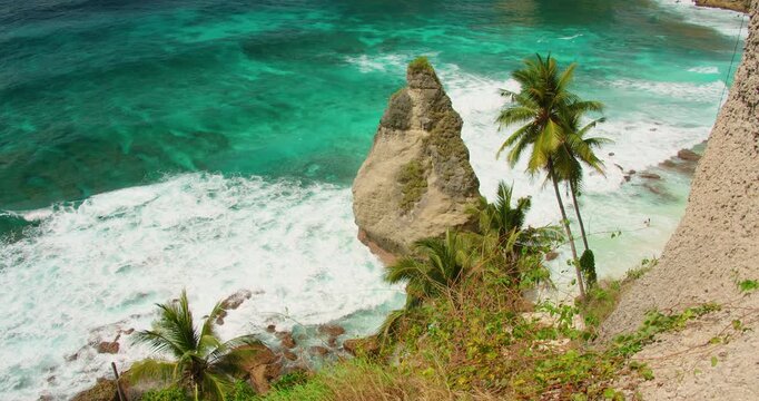 Jagged rock formation towers over crashing white surf at Diamond Beach in Nusa Penida