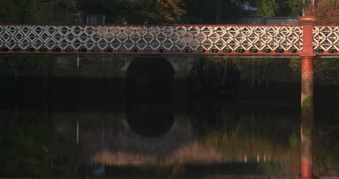 Pedestrian bridge diamond railings old arch bridge reflection on still river water