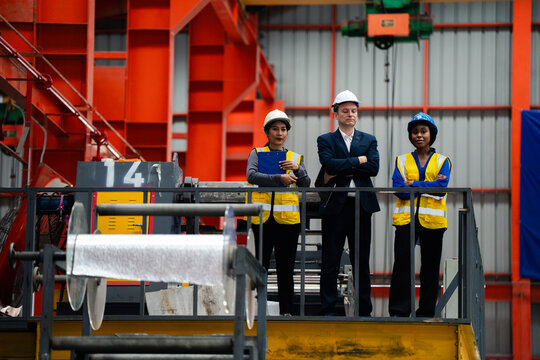 group of professional engineer, worker, technician discuss work, walk in steel metal manufacture factory plant industry. Black African American man and woman wear hard hat check quality machine