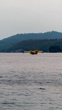 Firefighting Canadair aircraft flying and scooping water from an Italian lake during large forest wildfires, supporting aerial firefighting operations and wildfire suppression in Europe. 4K video