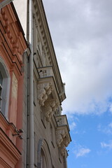Low angle view of historic building facades with ornate balconies, decorative corbels, and downspout pipes against a partly cloudy blue sky, architectural heritage concept. © Алина Неборская