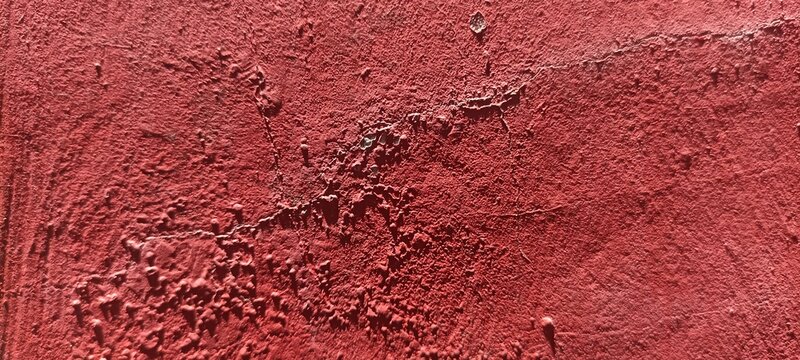 Red painted concrete texture background with heavy impasto distress, ideal for grunge artwork, industrial backdrops, striking banners, and high-contrast creative designs