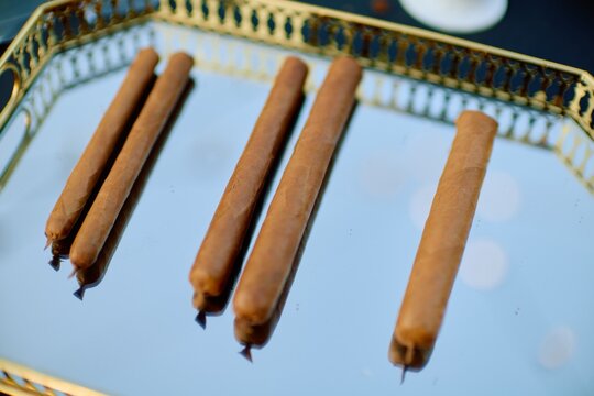 Premium Handmade Cigars on Elegant Gold Serving Tray with Reflective Surface