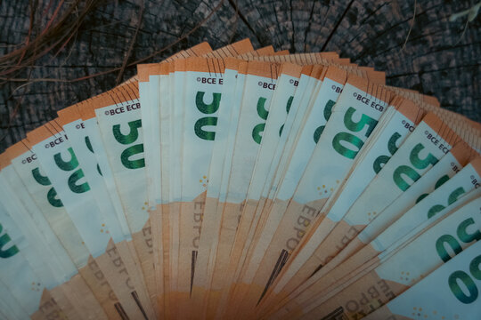 Fan of fifty euro banknotes arranged on a dark wooden surface as a concept of cash, wealth and personal finance